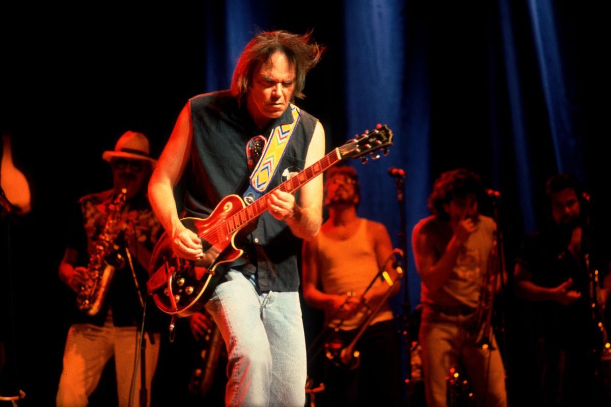 Canadian Folk and Rock musician Neil Young plays guitar as he performs, with his band, onstage at the Poplar Creek Music Theater, Hoffman Estates, Illinois, August 15, 1986