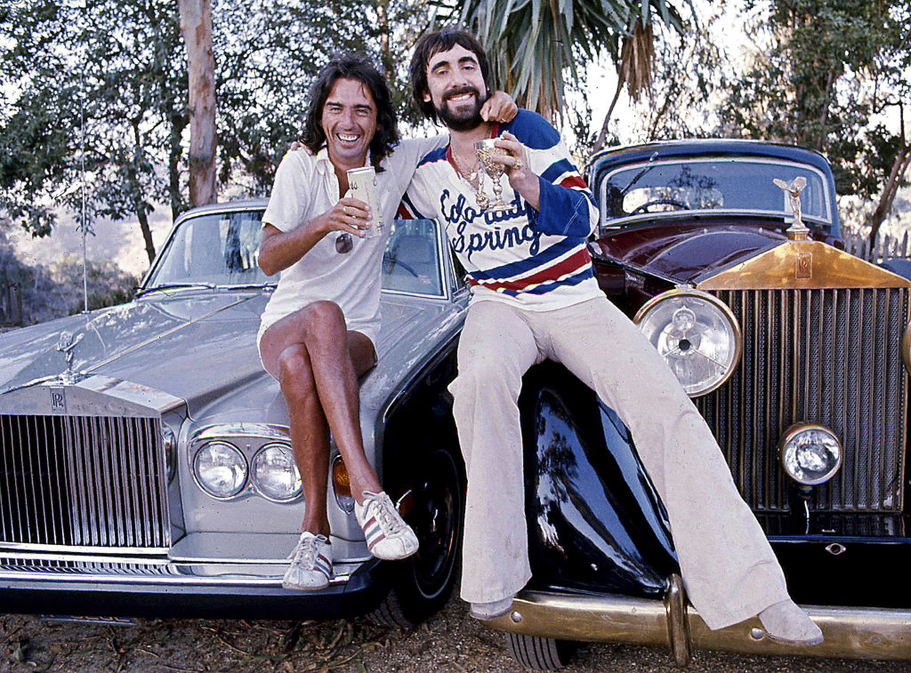 Rock stars Alice Cooper and Keith Moon share a cocktail on the hoods of their Rolls-Royces on Mulholland Drive, Los Angeles, June 1976