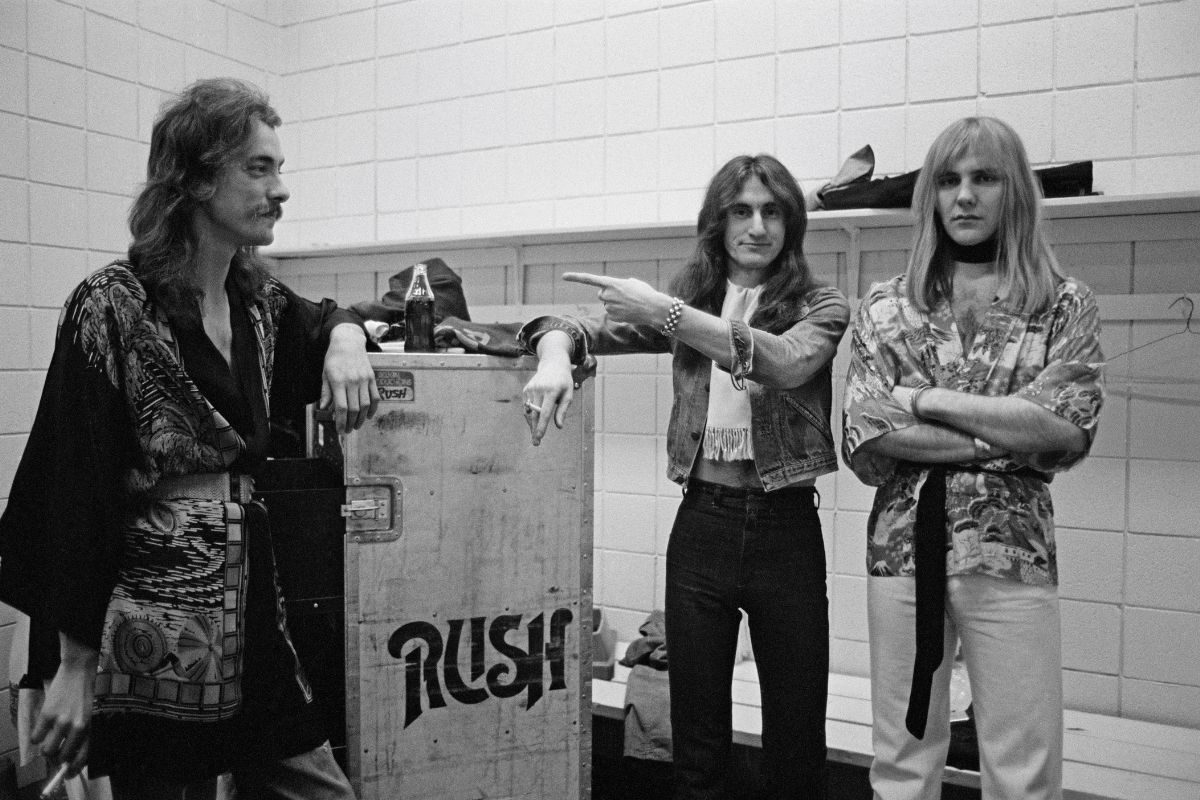 L-R Rush band members Neil Peart, Geddy Lee and Alex Lifeson backstage in Springfield, Massachusetts, 9 December 1976 during their All The World's a Stage tour