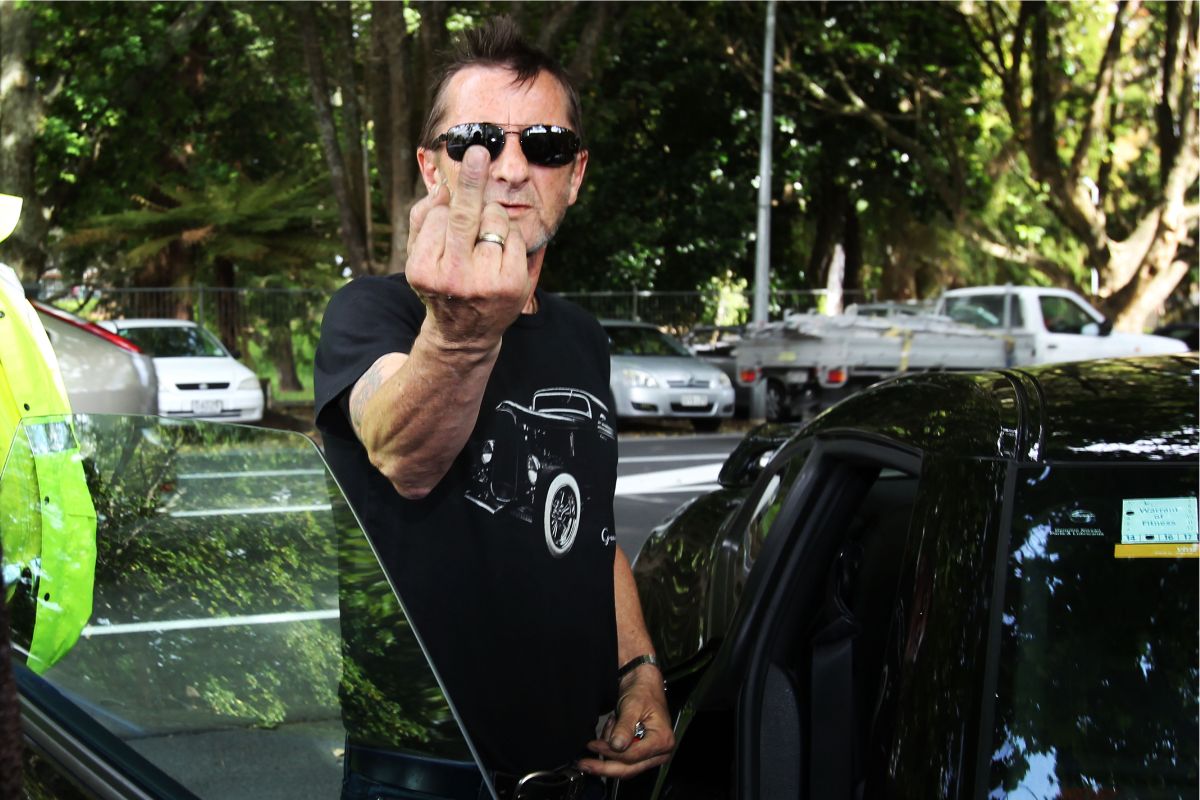 Phil Rudd gestures to the media after being charged with threatening to kill and possession of meth and marijuana, Tauranga District Court, 26 November 26, 2014