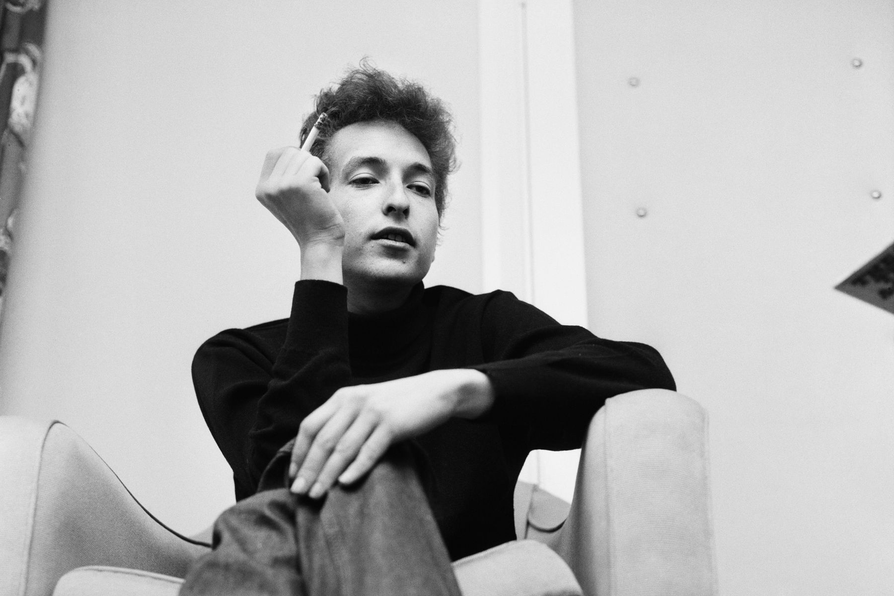 Bob Dylan smokes a cigarette in his hotel room during his visit to London. 11th May 1964