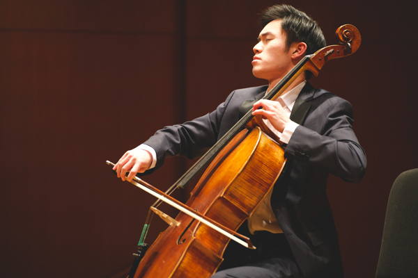 Young male in a black suit playing the cello