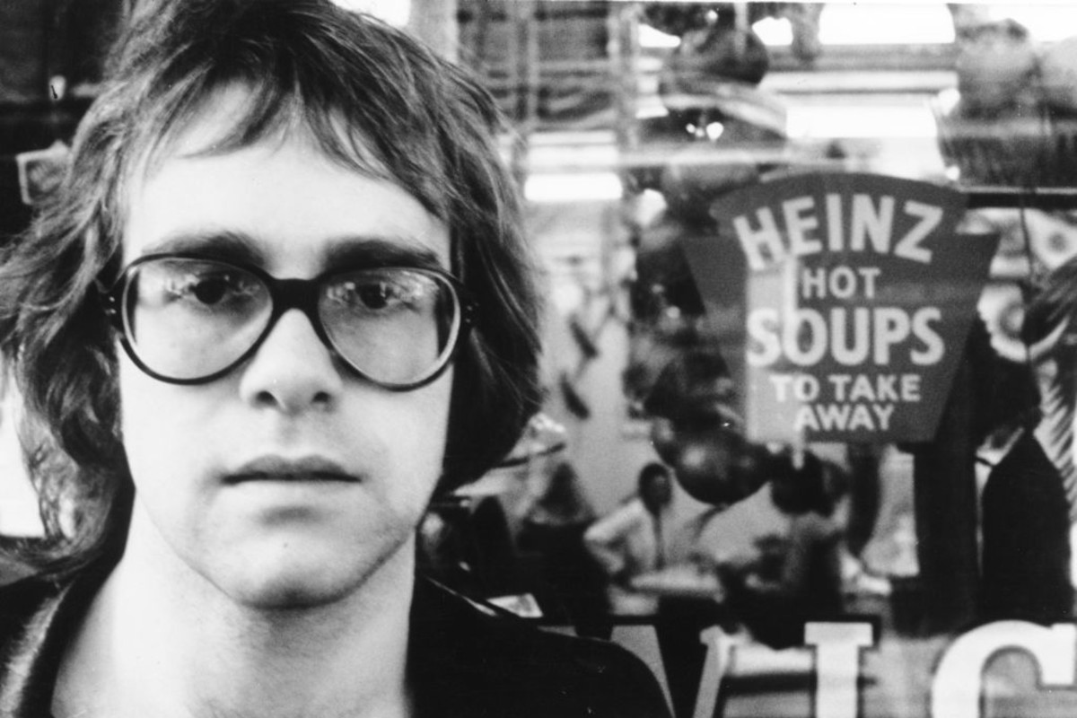 Elton John looking cool in front of a sign that says "Heinz Hot Soups", circa 1970
