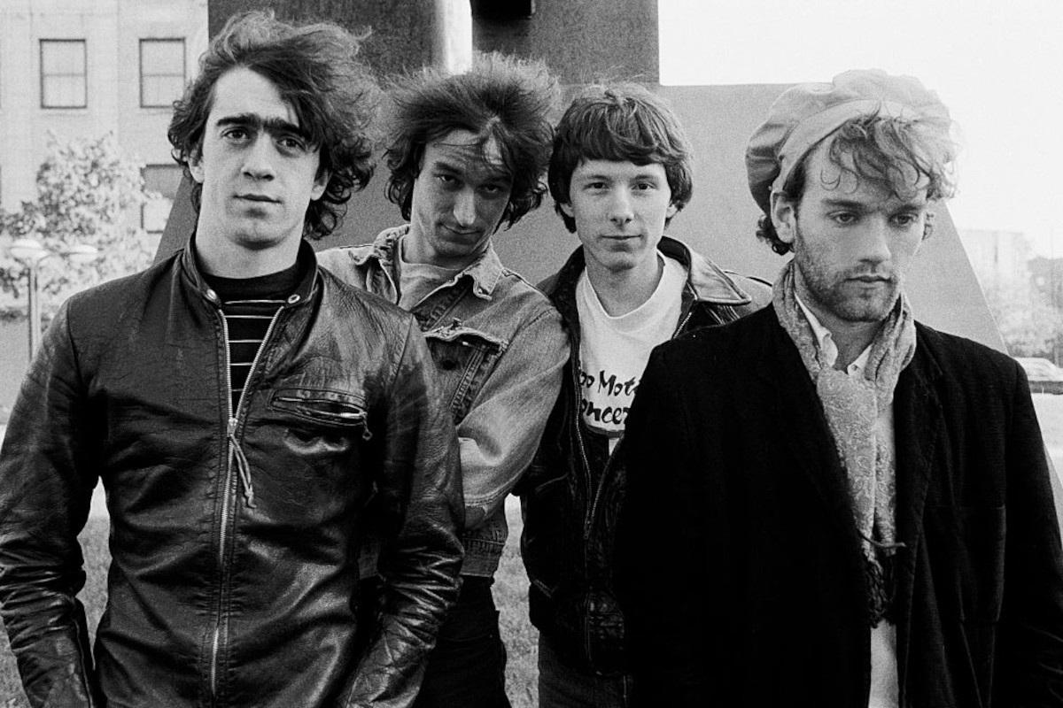 REM posing outdoors next to a sculpture at Park West, Chicago, May 26, 1983