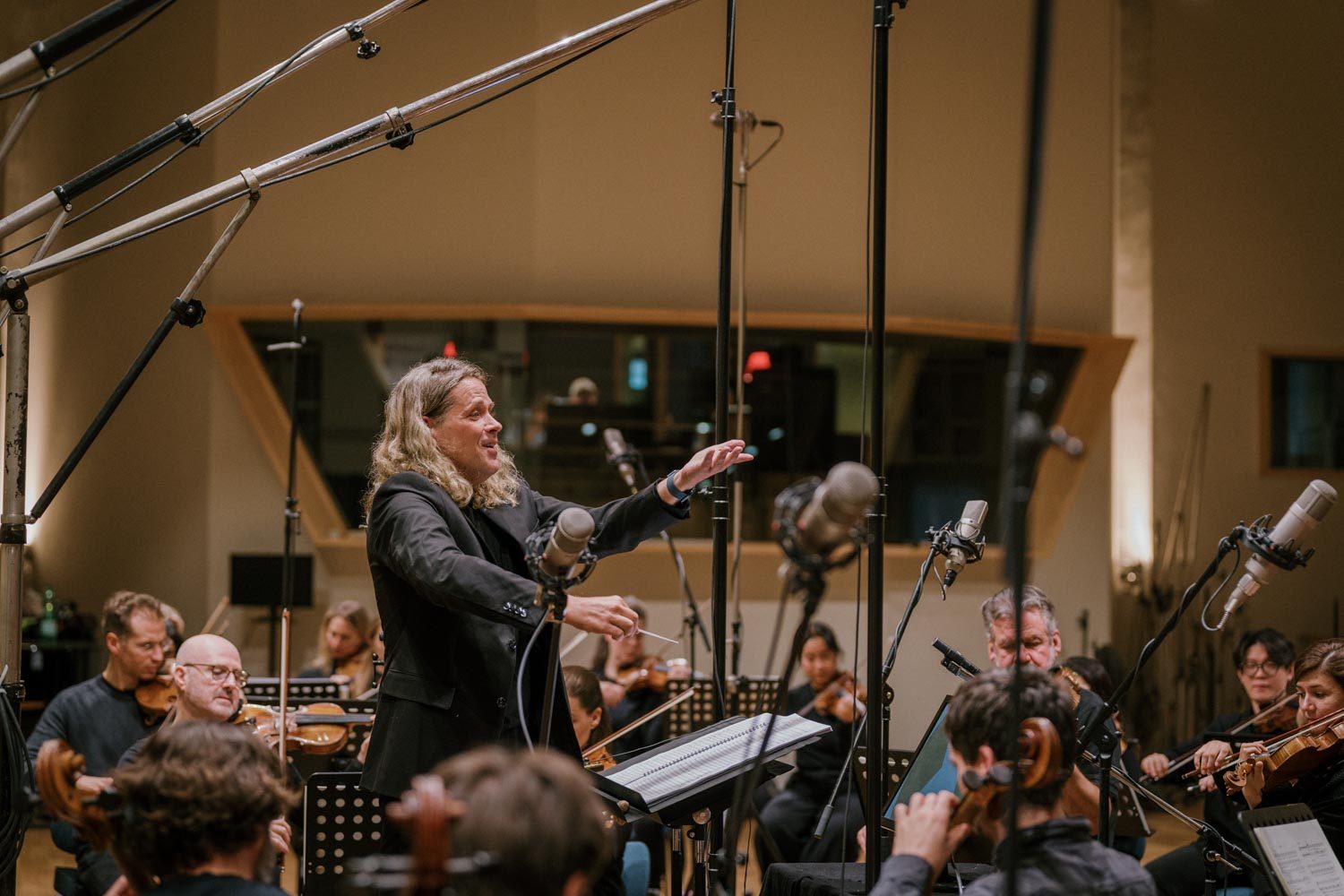 Nathan Henninger conducting an  orchestra in a recording studio
