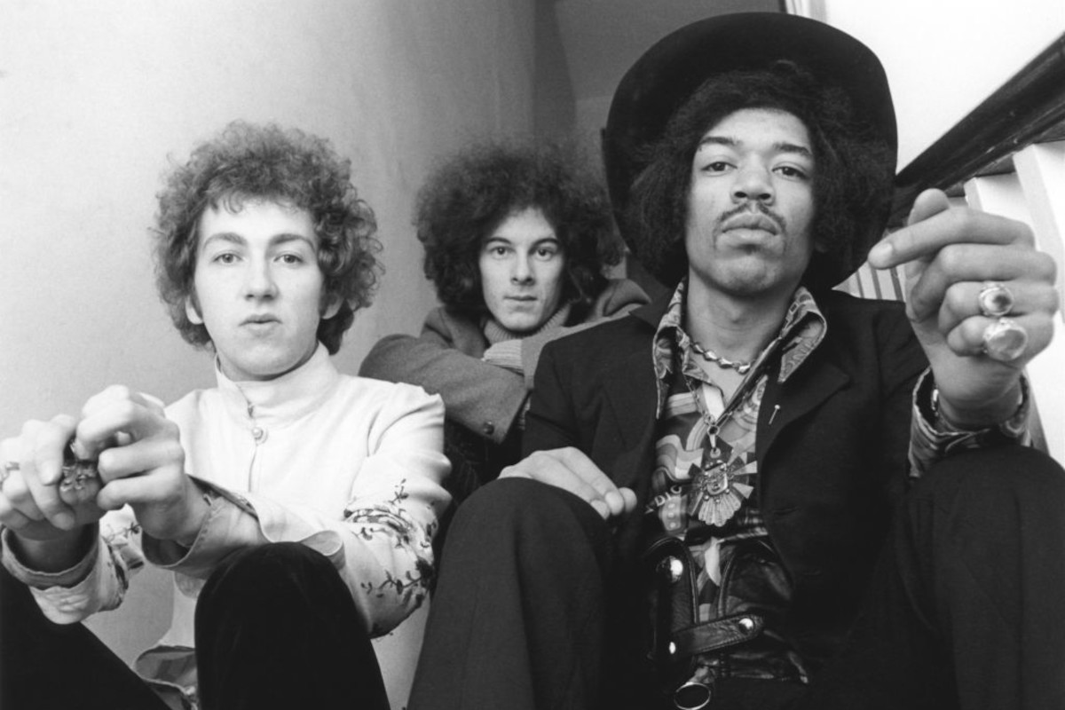 Jimi Hendrix seated on right with, on left, Mitch Mitchell and, behind in centre, Noel Redding, August 1967