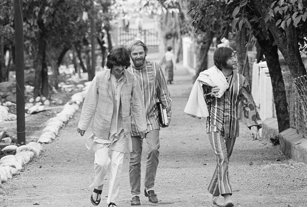 George Harrison and John Lennon, sporting Indian attire and joined by Mike Love of the Beach Boys, stroll through a street in Shankaracharyyanagar in Northern India during their sojourn at Rishikesh