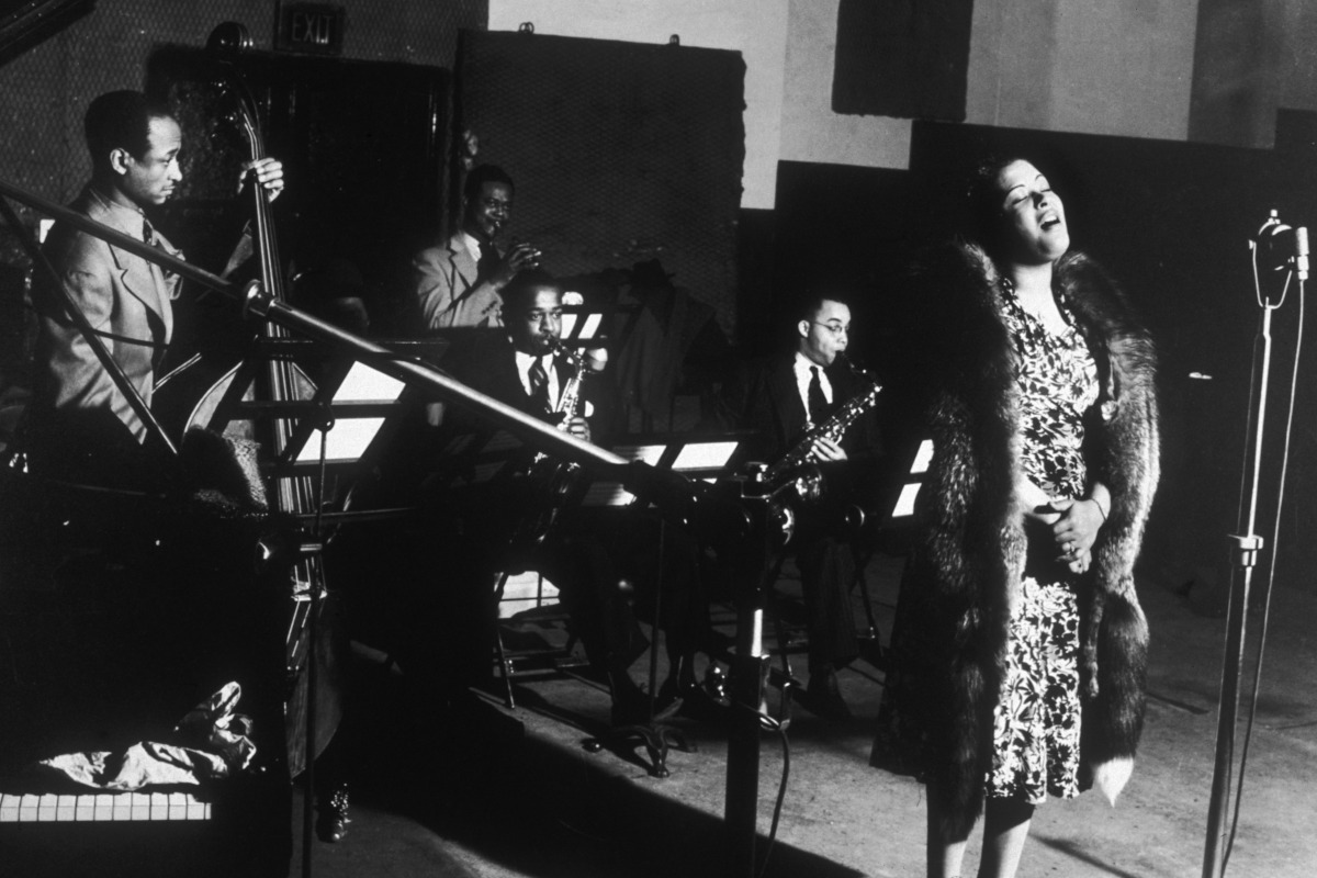 American jazz singer Billie Holiday performs with, left to right; bassist Johnny Williams, trumpeter Frankie Newton and saxophonists Stan Payne and Kenneth Hollon at a Commodore Records recording session