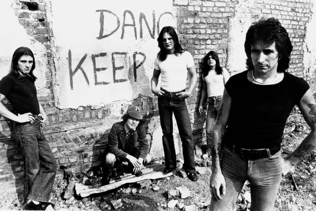 Australian rock group AC/DC pose for an Atlantic Records publicity still in front of a graffiti-covered wall circa 1977. (L-R:) drummer Phillip Rudd, guitarist Angus Young, bassist Mark Evans, guitarist Malcolm Young, and lead singer Bon Scott
