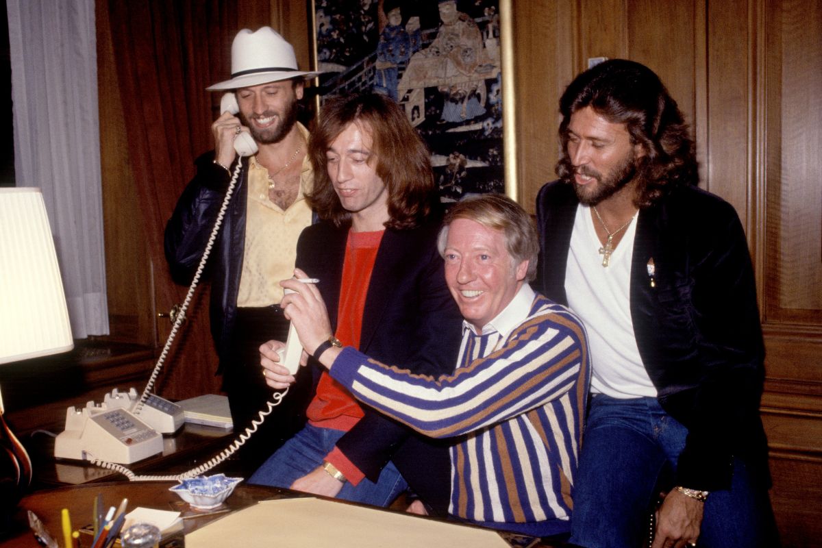 The Bee Gees at RSO records (L-R) Maurice Gibb (on telephone), Robin Gibb, manager Robert Stigwood and Barry Gibb posed in Stigwood's office in New York in 1980