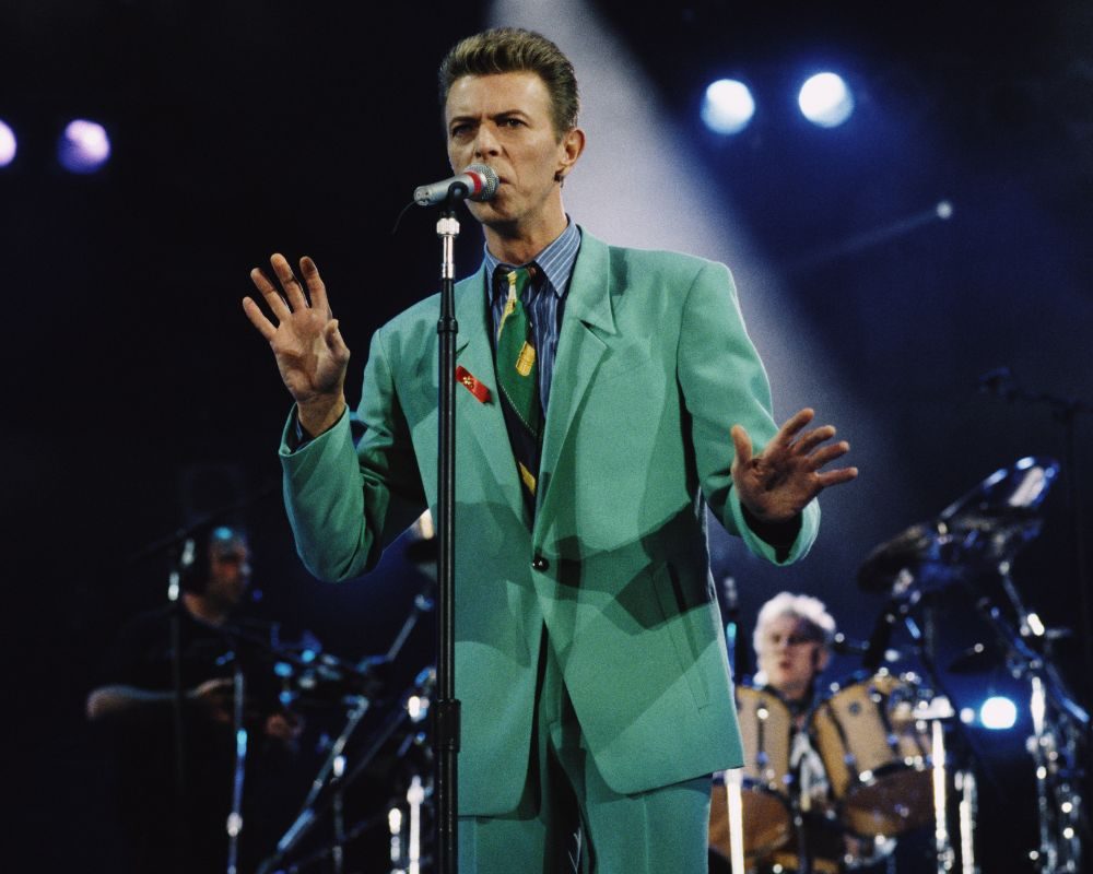 David Bowie (1947 - 2016) performs on stage at the Freddie Mercury Tribute Concert for AIDS Awareness, Wembley Stadium, London, 20th April 1992. Queen drummer Roger Taylor performs behind