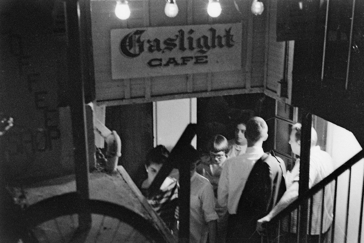 View, looking down a staircase, of people in the entrance of the Gaslight cafe, New York, circa 1960