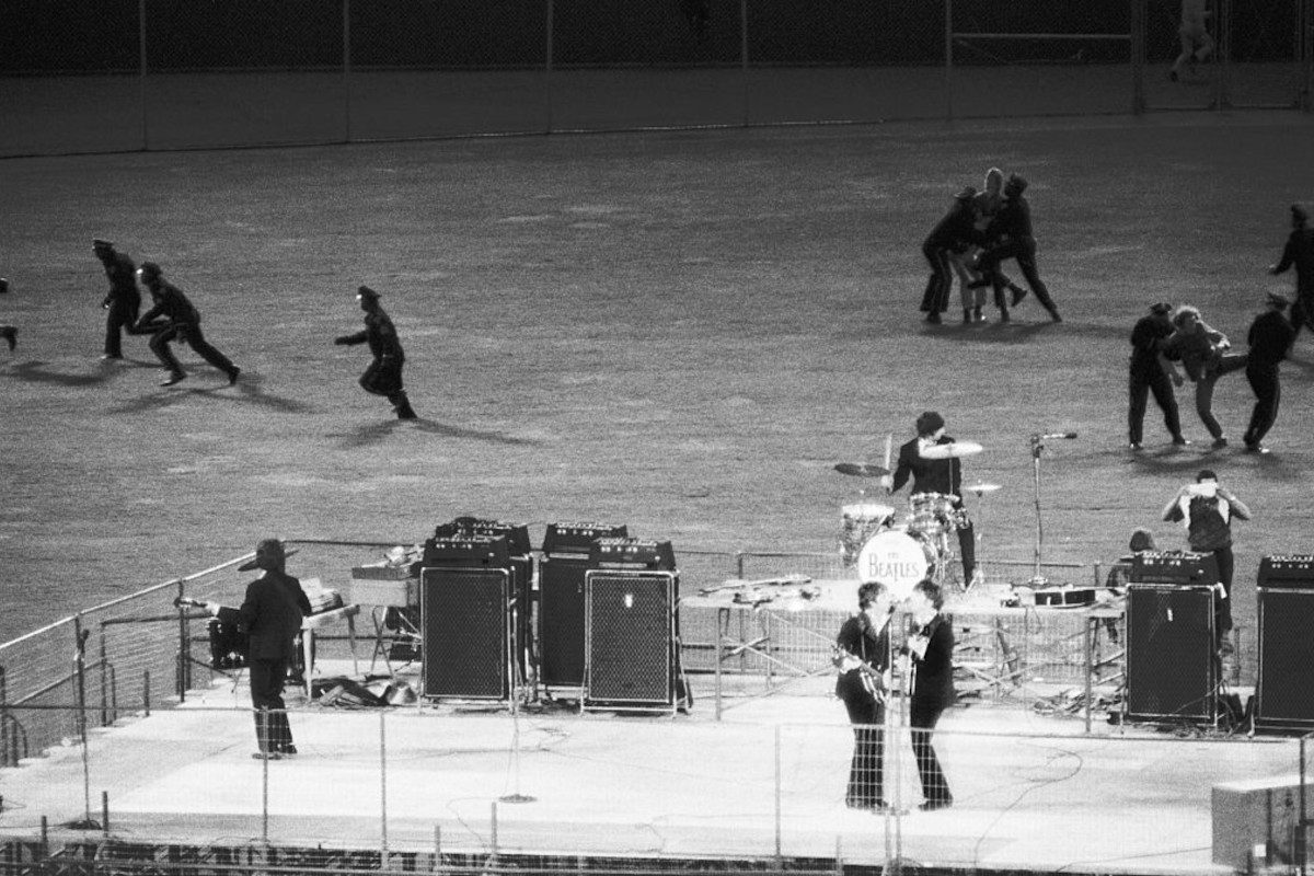 Policemen clear the field of enthusiastic fans as The Beatles perform on a bandstand in Candlestick Park, San Francisco, California