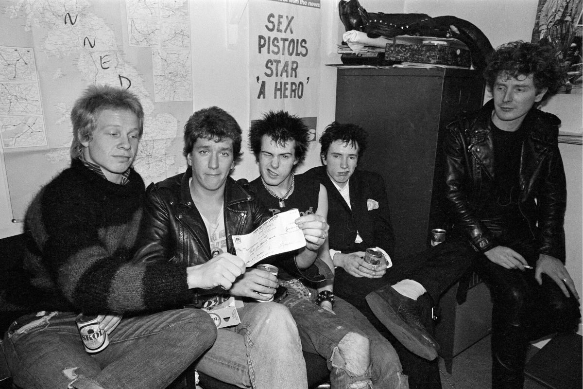 17 March 1977: the Sex Pistols (L-R Paul Cook, Steve Jones, Sid Vicious, Johnny Rotten) with a £25,000 cheque from A & M Records, who have just fired them. Manager Malcolm McLaren looks on
