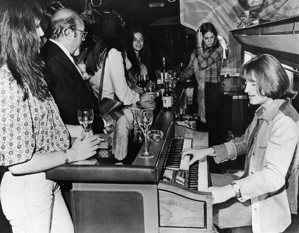 John Paul Jones plays a Thomas electric organ behind the bar on board Led Zeppelin’s private jet known as 'The Starship', 30 July 1973