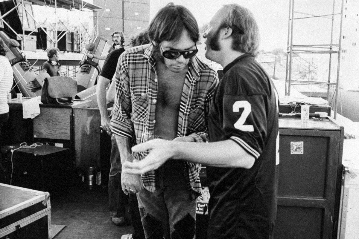 Stephen Stills (right) and Neil Young talk backstage before a Crosby, Stills, Nash, and Young concert, 1974