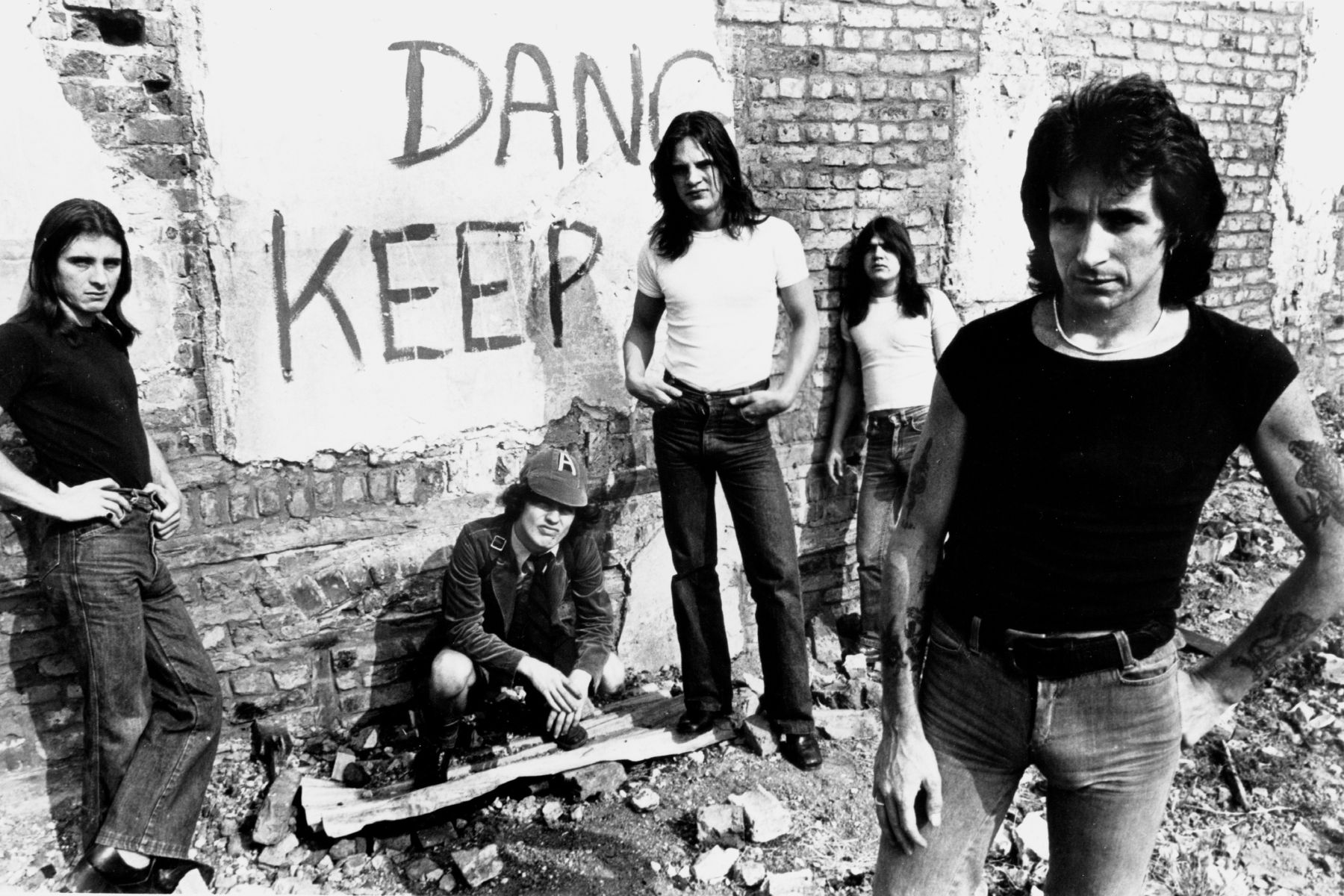 AC/DC pose for an Atlantic Records publicity still in front of a graffiti-covered wall circa 1977