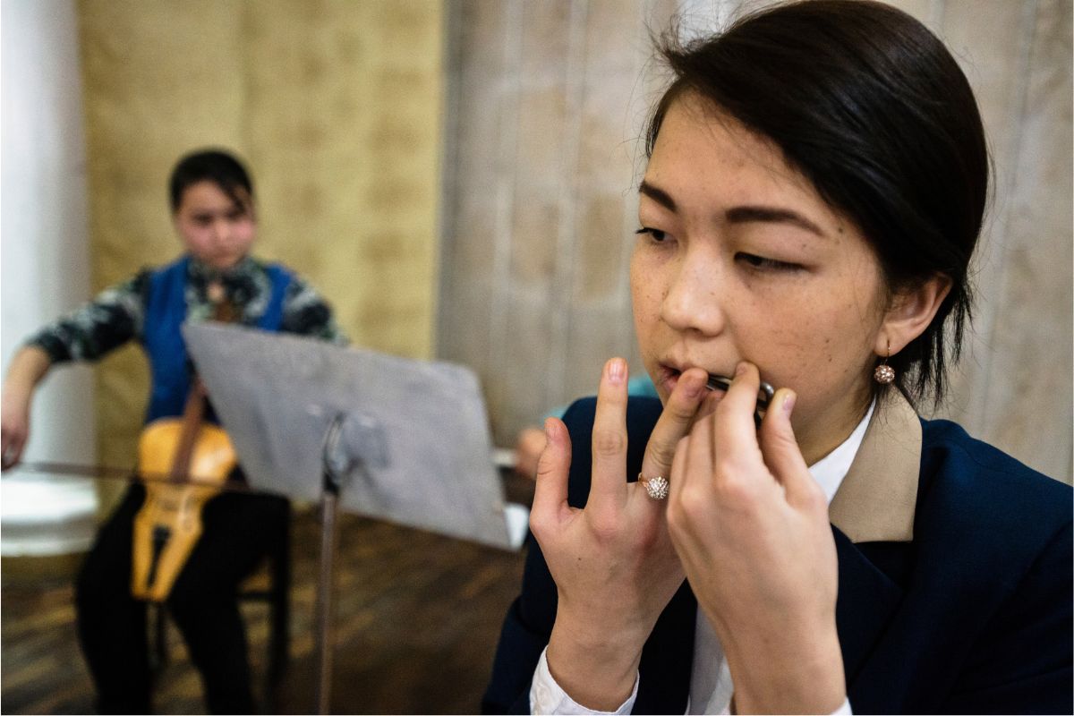 Girl plays temir komuz, Kyrgyz Jew's harp, in Kyrgyz authentic musical instruments orchestra in Bishkek musical college, Bishkek, Kyrgyzstan