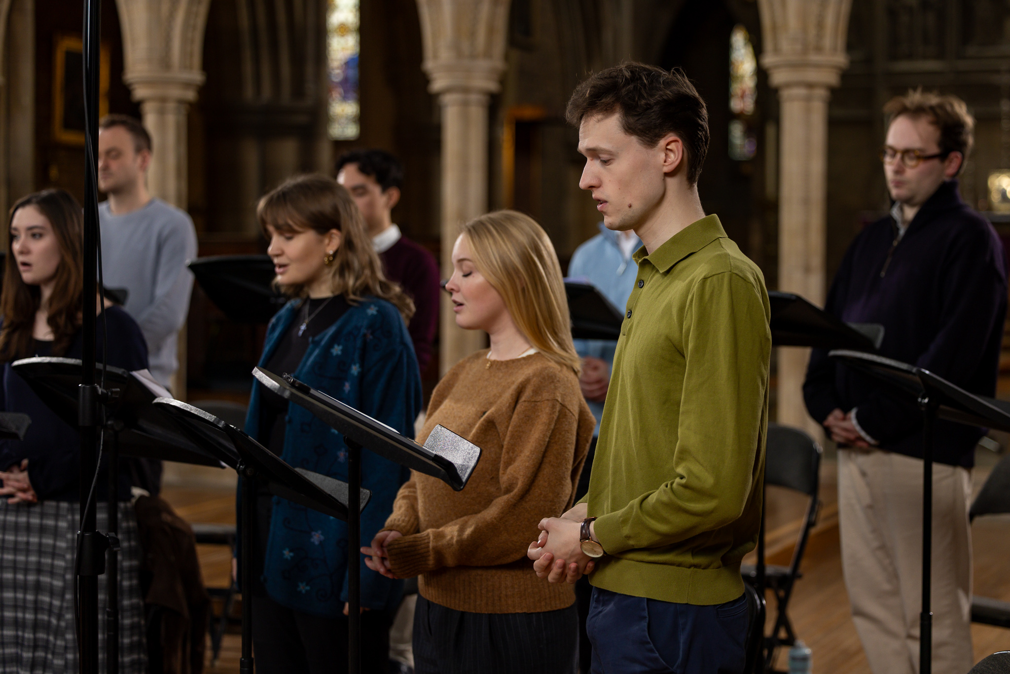 Group of young adults singing in a church behind music stands