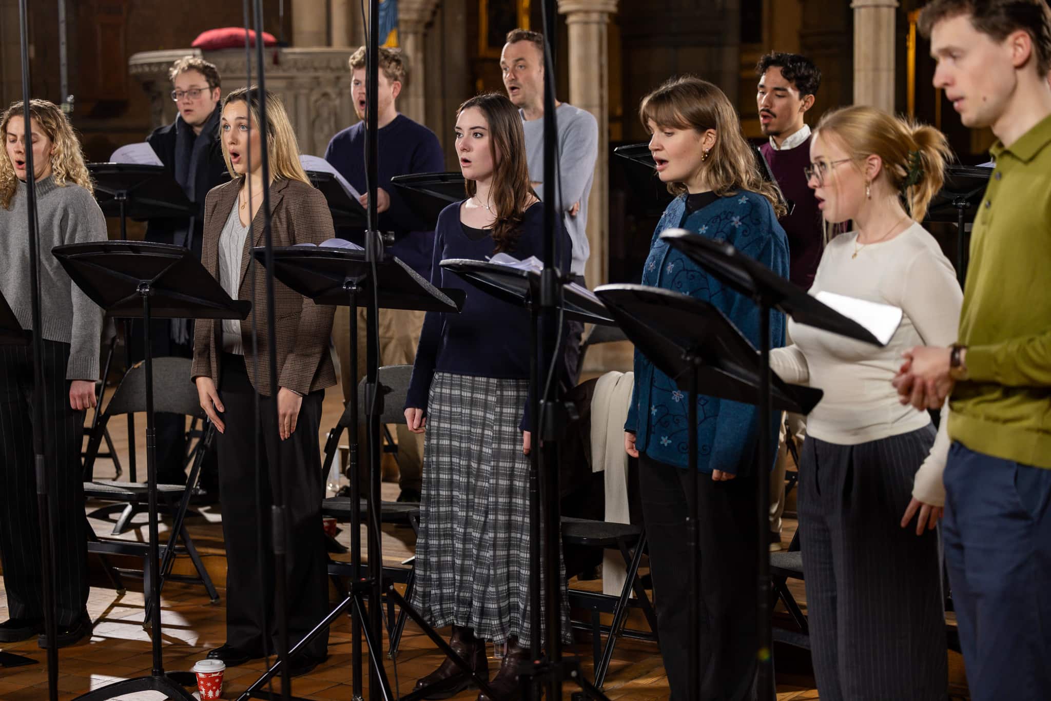 Choir of young adults singing in a church behind music stands