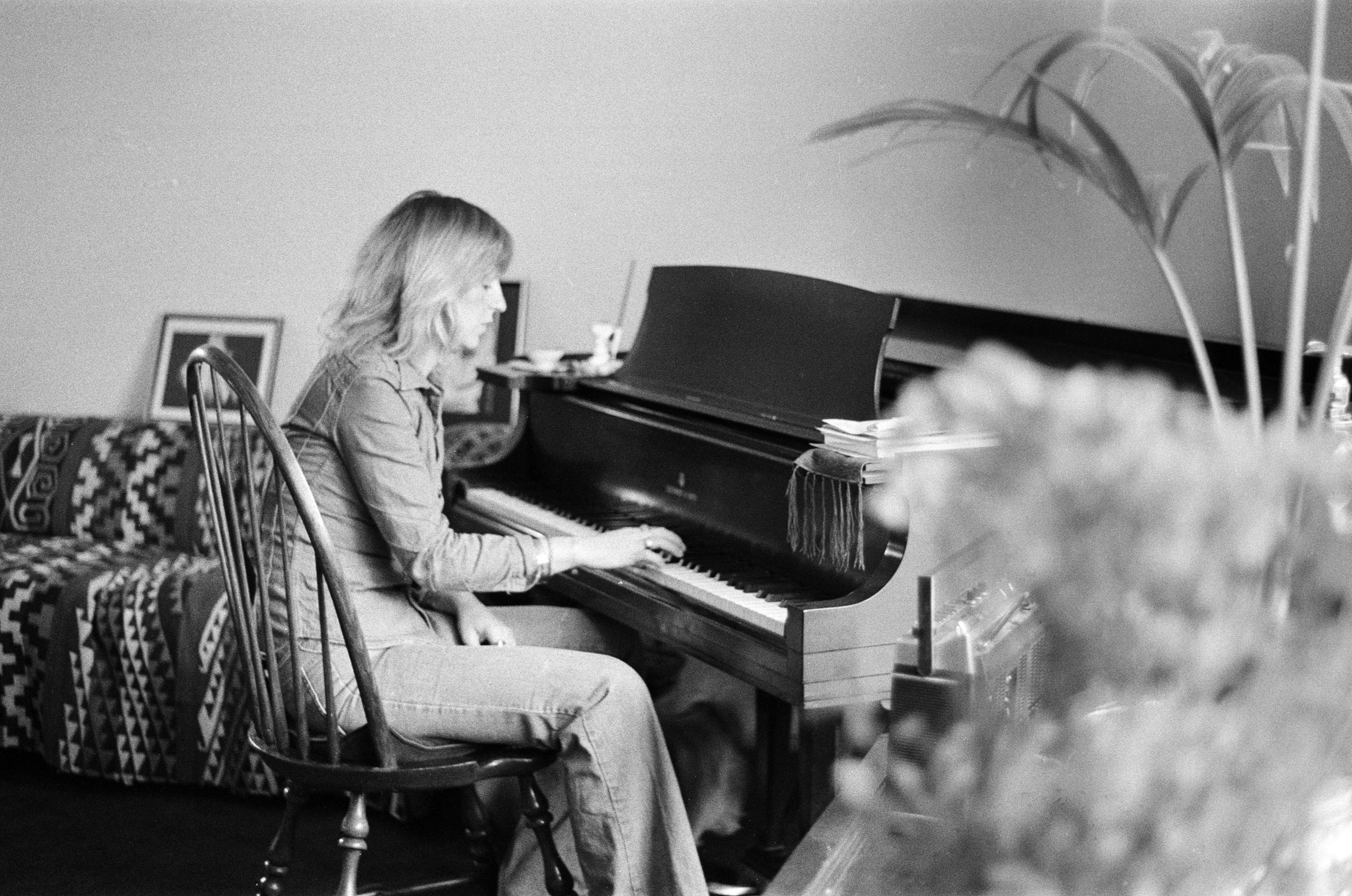 Black and white photo of Christine McVie sitting at a piano