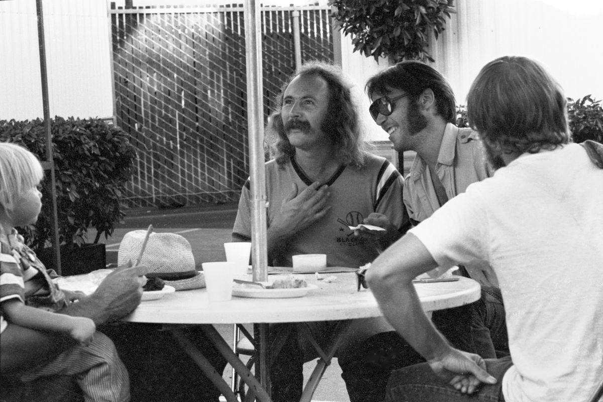 L-R Amber Young, child of Neil Young, with David Crosby, Young, and Tim Drummond, backstage at Oakland Colisseum, California on July 14 1974 during the Crosby, Stills, Nash and Young 1974 US Tour