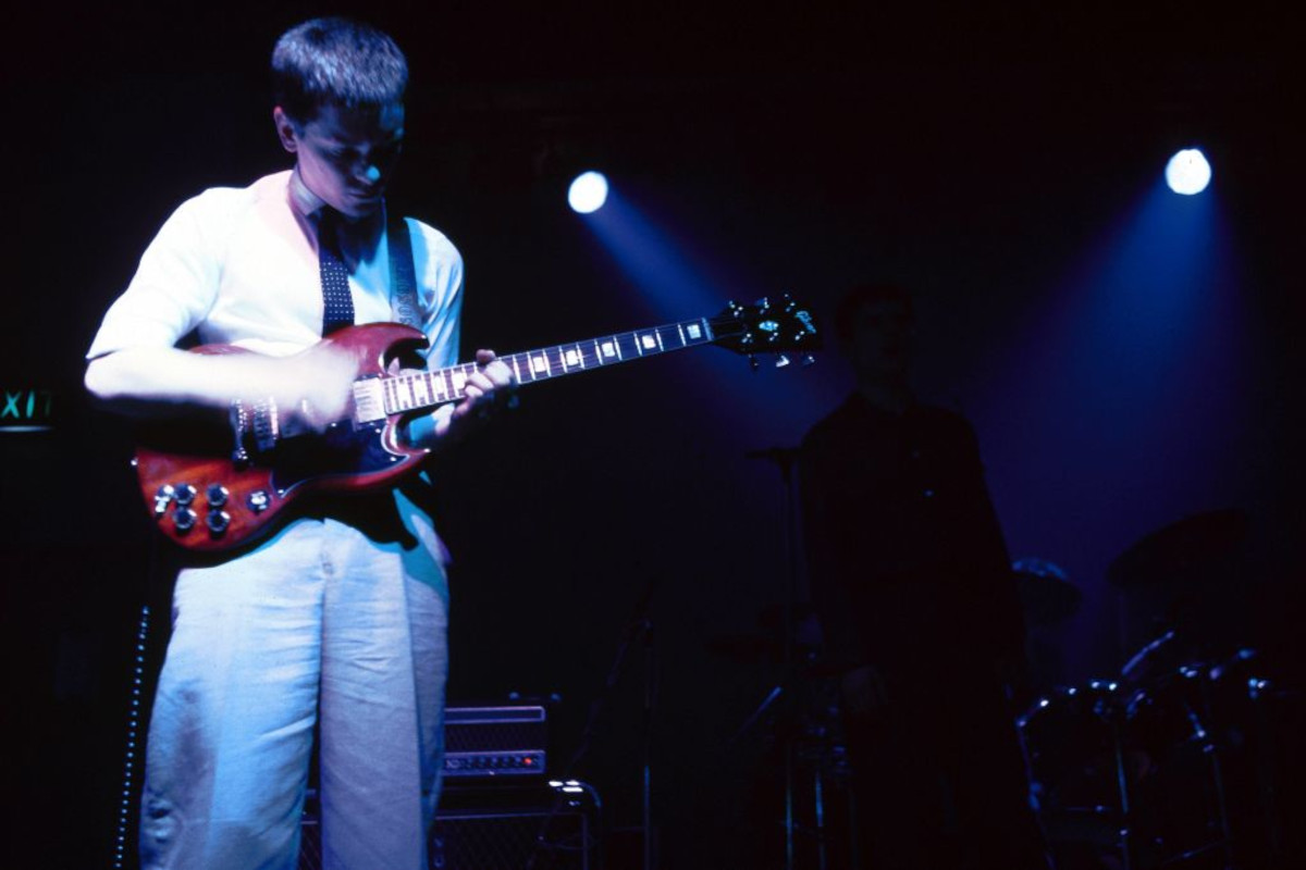 Bernard Sumner performing live with Joy Division onstage, playing Gibson SG guitar, 1979