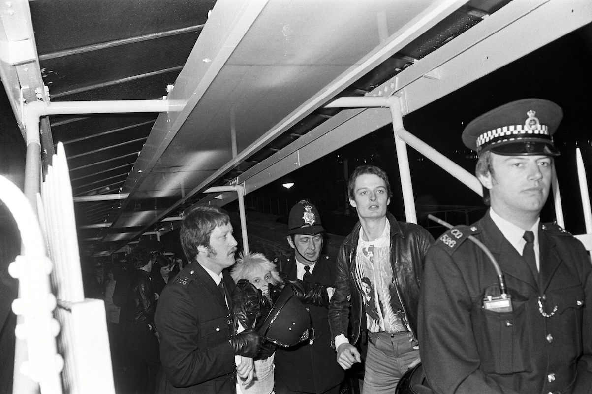 Black and white photo of Vivienne Westwood and other guests as they are taken away by police