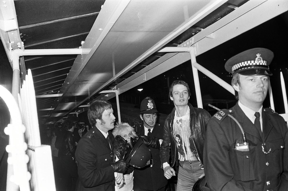 Black and white photo of Vivienne Westwood and other guests as they are taken away by police