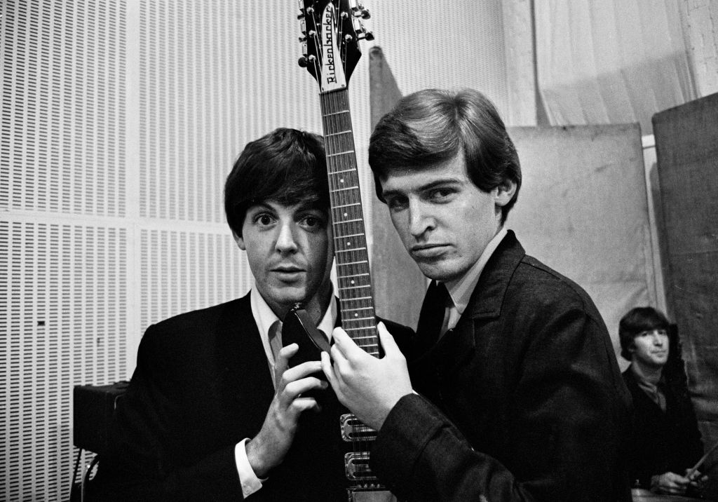 The Beatles' Paul McCartney, left, posing with his brother, musician Mike McGear (Mike McCartney), August 18th 1964. John Lennon is seated in the background.